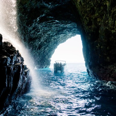 Boat inside a seaside cave with water flowing and light entering from the entrance.