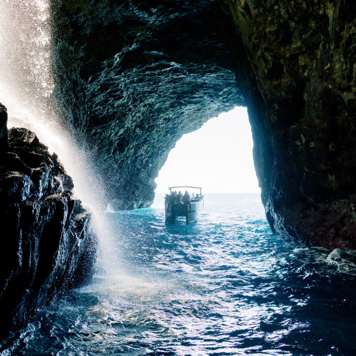 Boat inside a seaside cave with water flowing and light entering from the entrance.