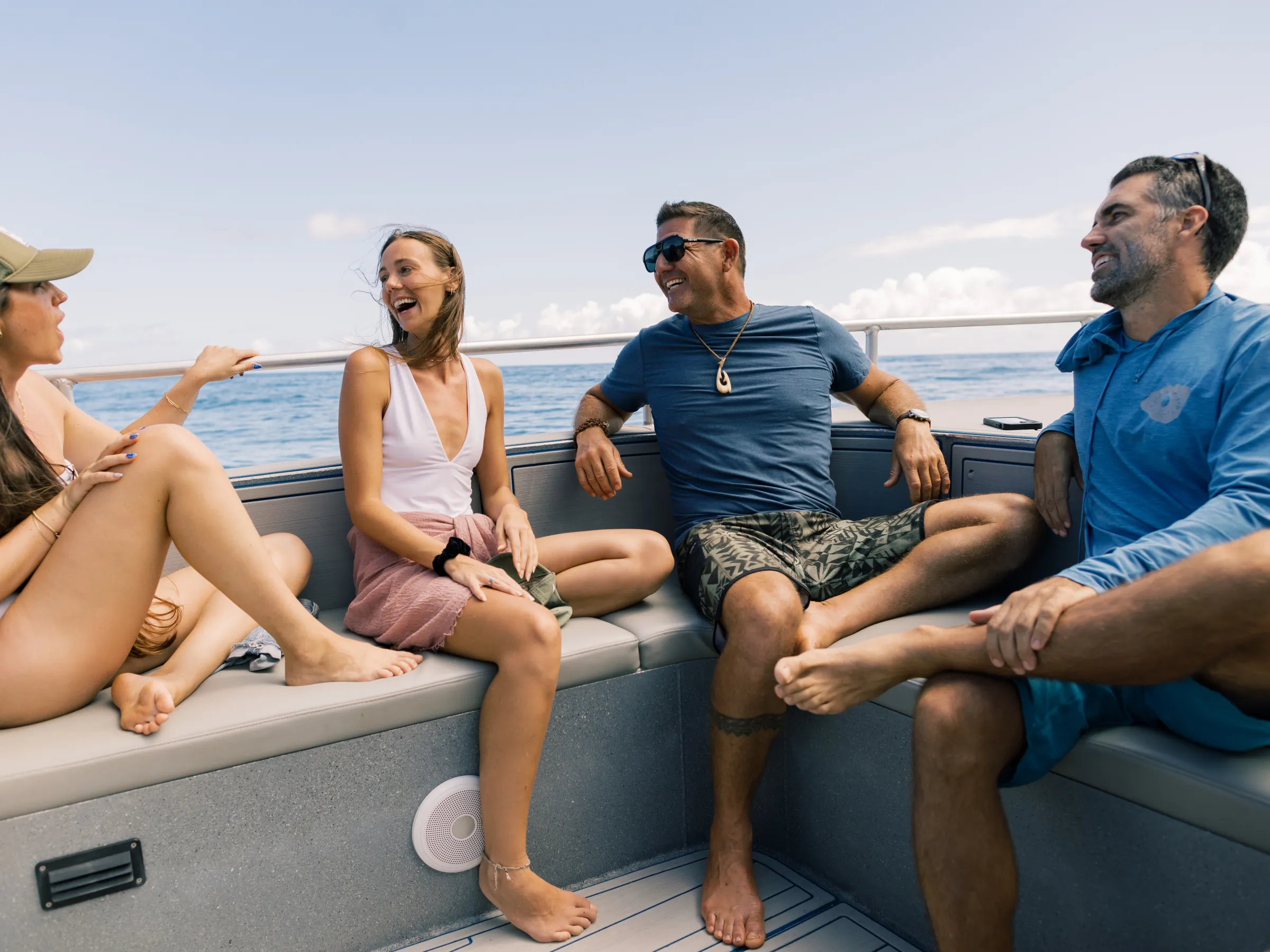Four people smiling and talking on a boat with an ocean view.
