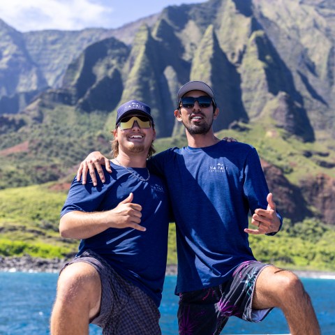 Two men posing with mountains and ocean in the background.